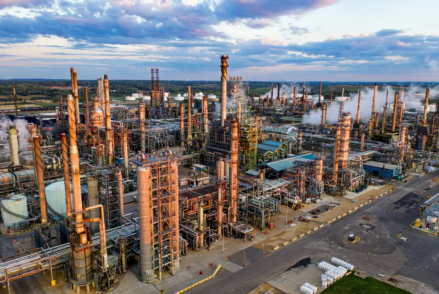 Refinery towers, pipework and processing infrastructure beneath a blue sky