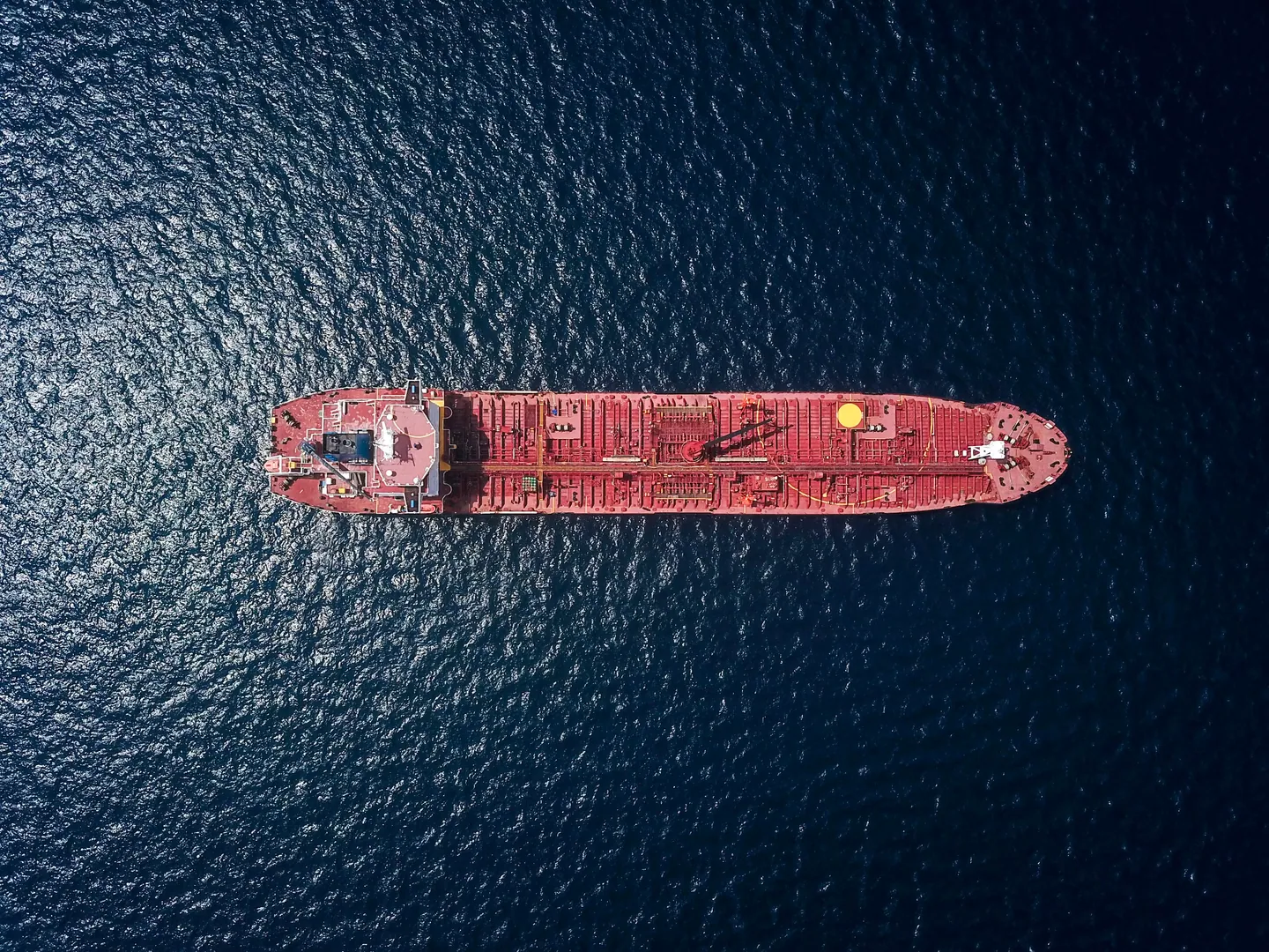 Overhead view of a red tanker crossing deep blue water